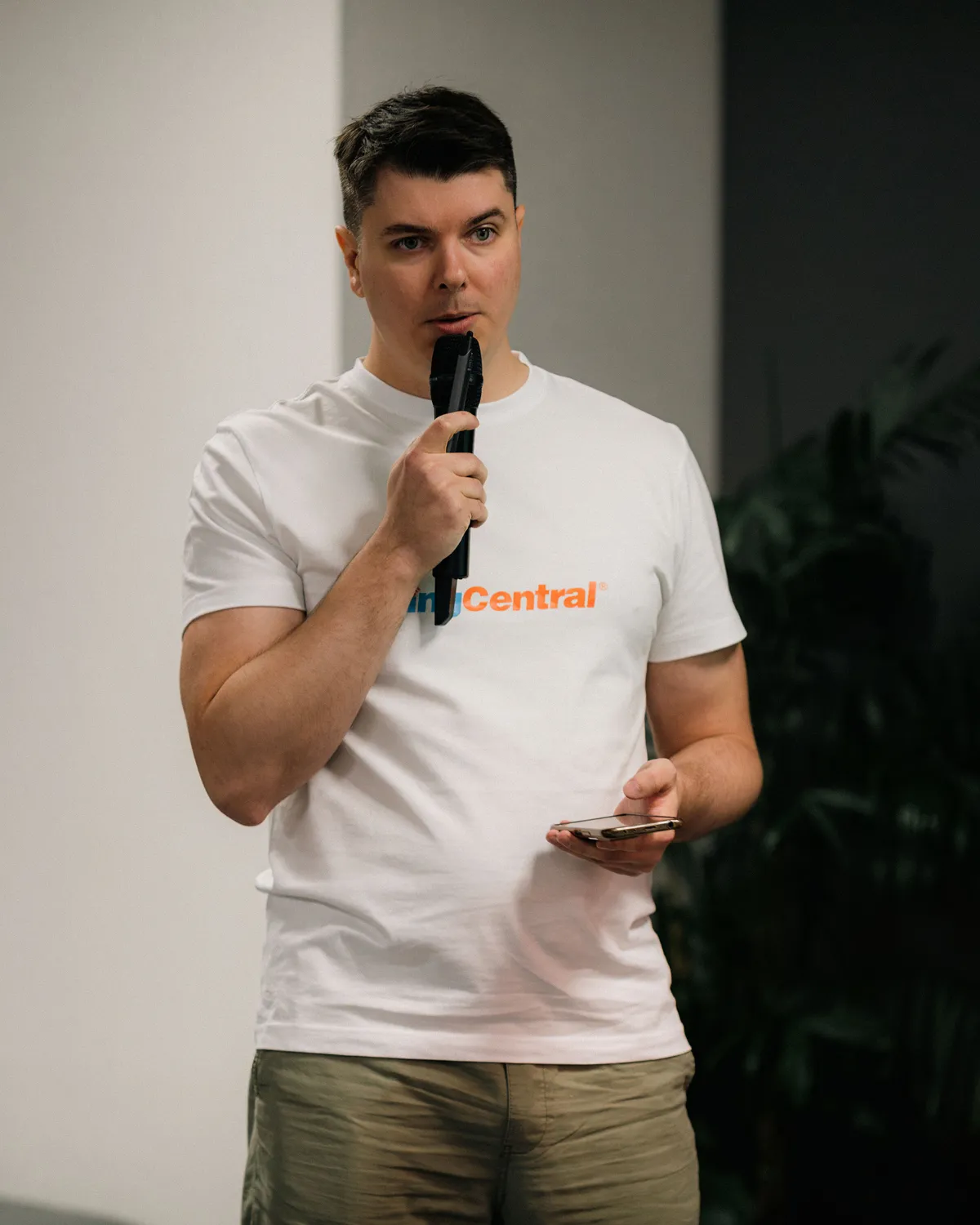 Служител, който изнася доклад, говори в микрофон и е облечен с тениска на RingCentral.