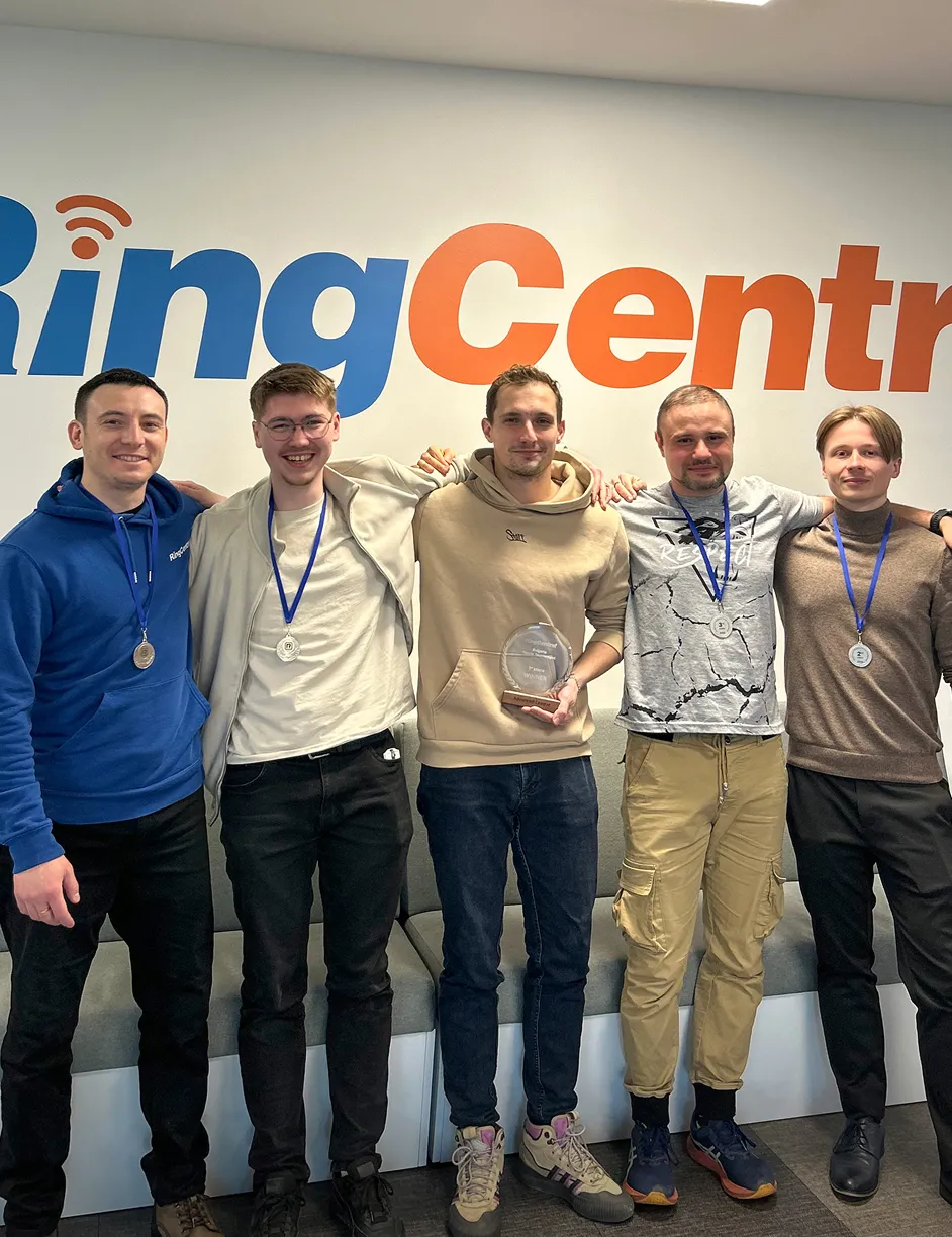 Пет служители на RingCentral с медали, като човекът в центъра държи трофей.