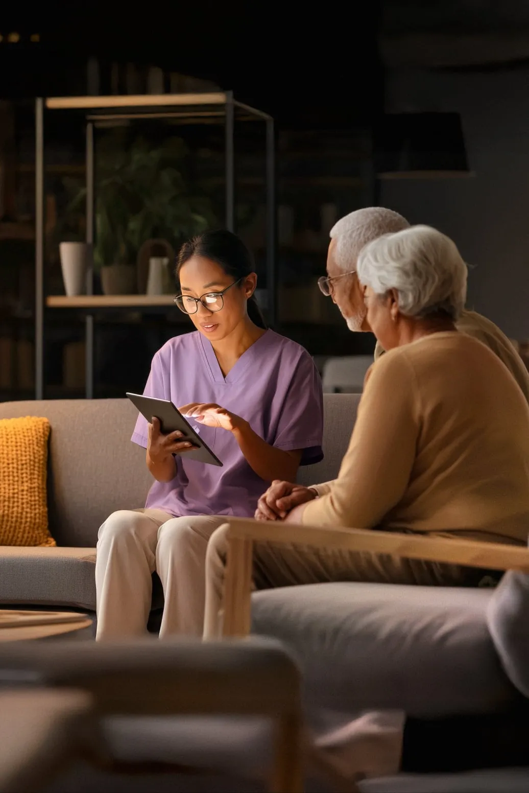Healthcare worker showing a digital tablet to an elderly couple.