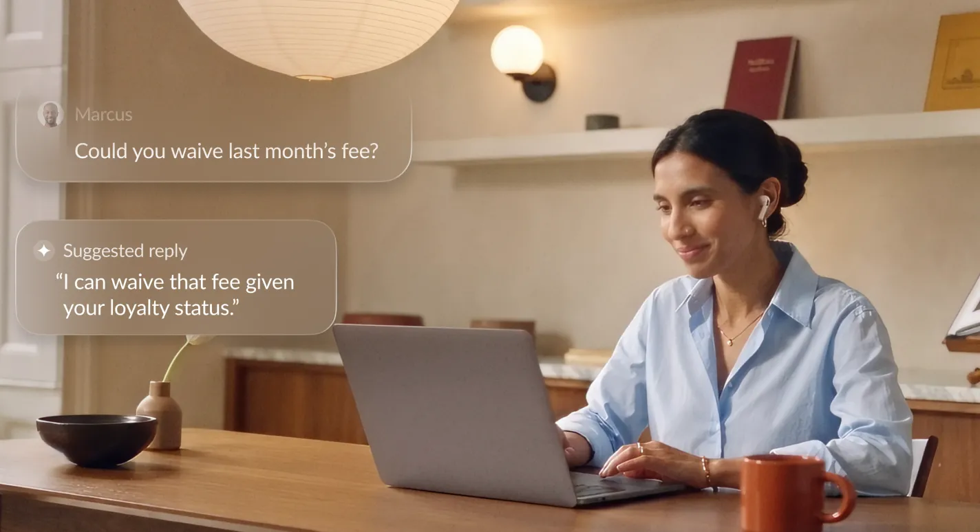 A contact center agent works on a laptop while RingCX shows a customer message, "Could you waive last month’s fee?", and an AI suggested reply.