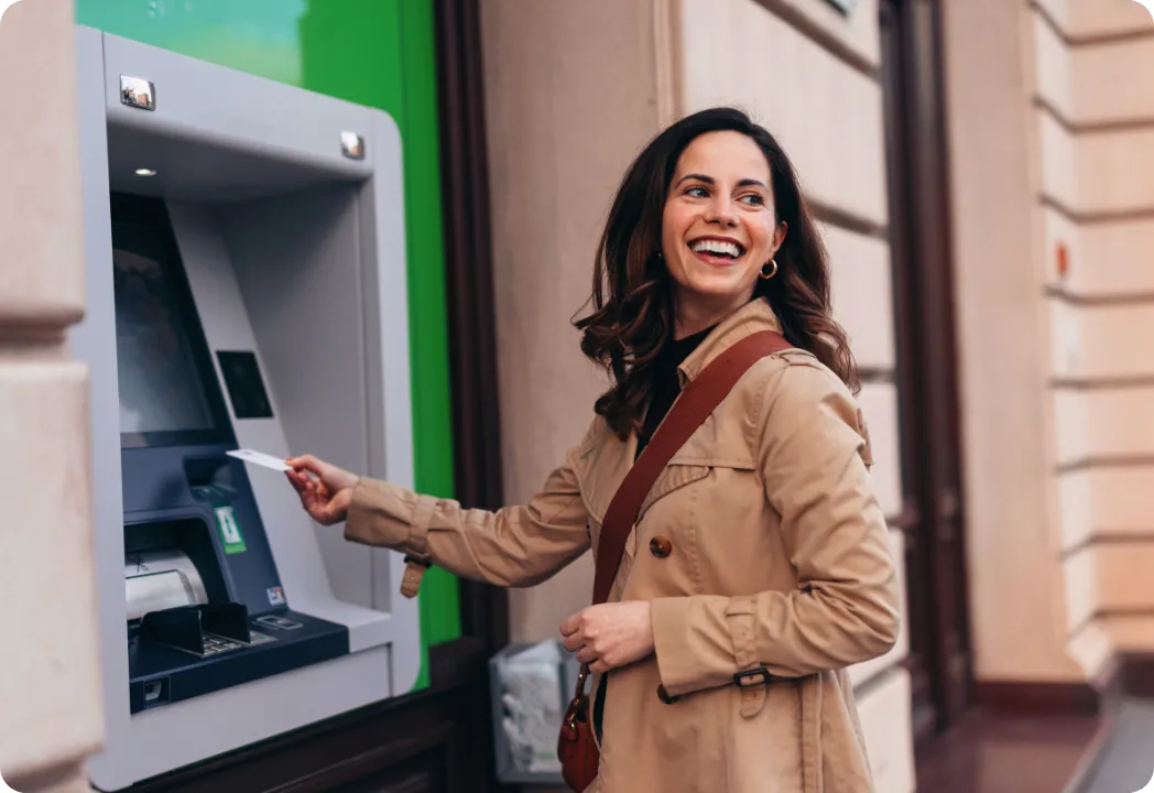 Woman using an ATM machine outside on a city street.