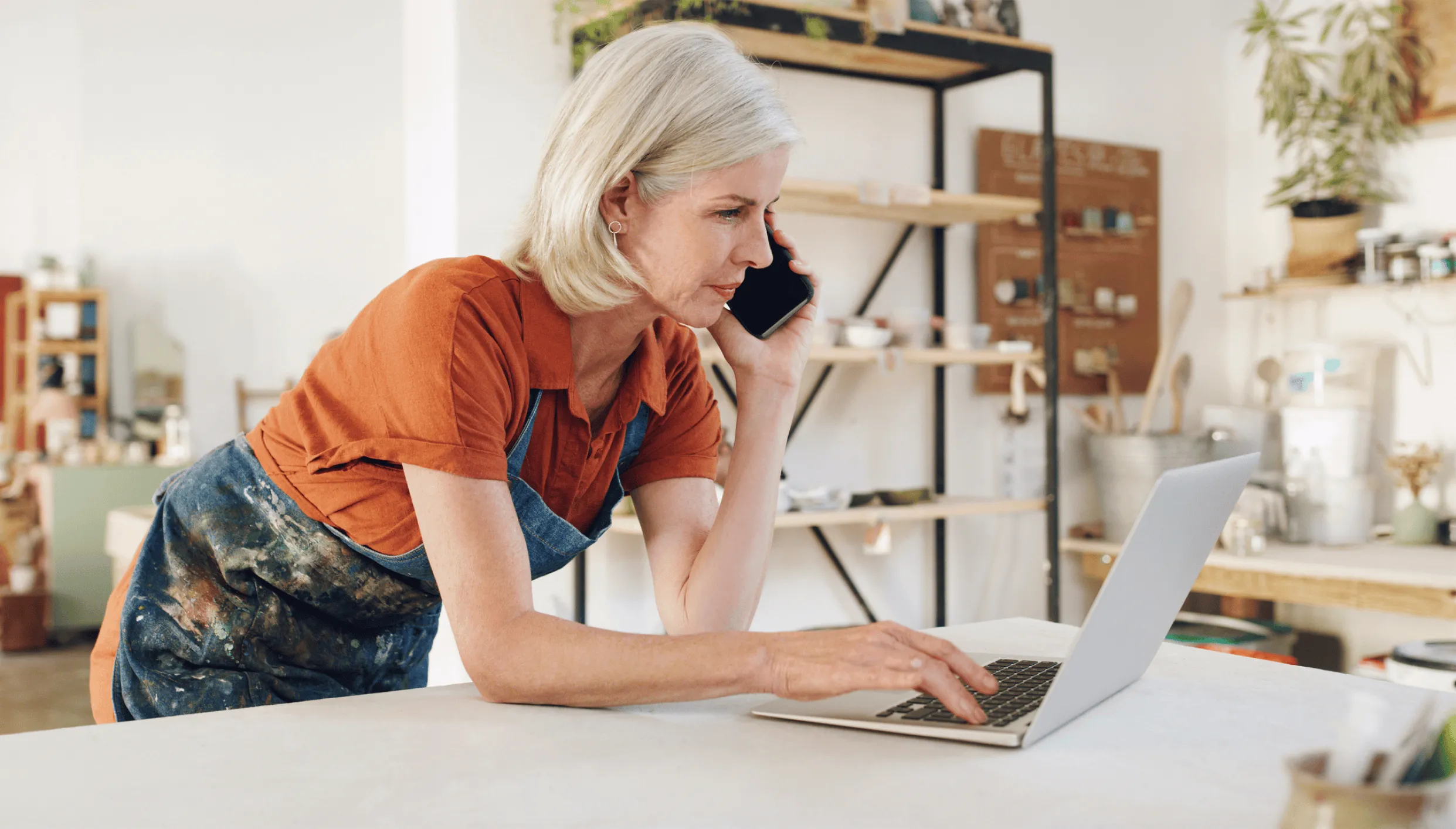 An artist taking a call on her mobile while messaging on her laptop using RingEX