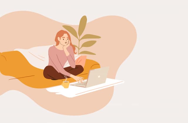 Woman using computer while sitting on sofa at home