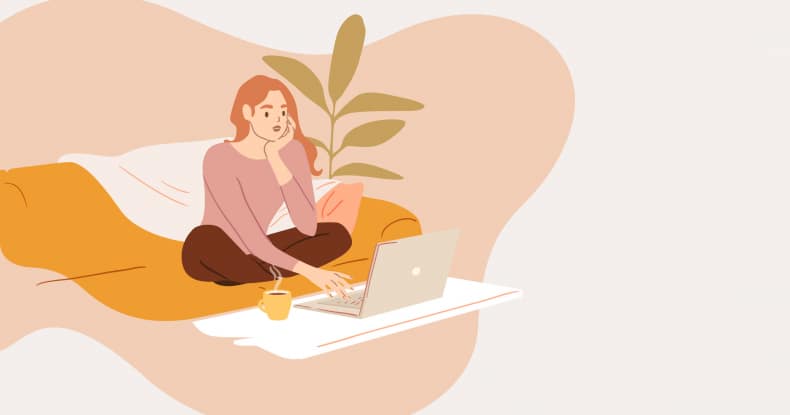 Woman using computer while sitting on sofa at home