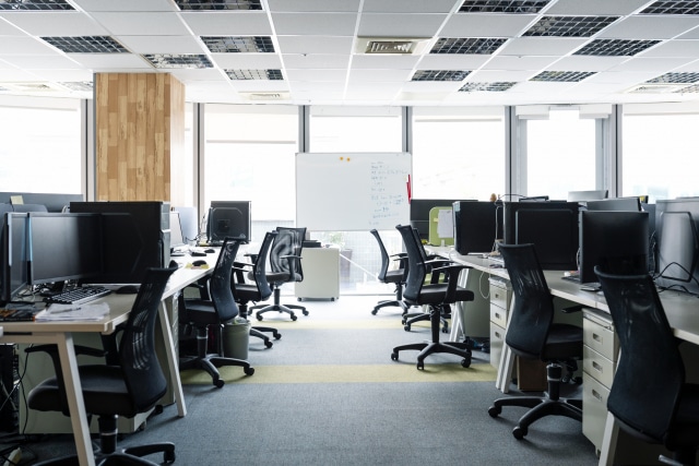 empty chairs and desktop pcs at desks in office