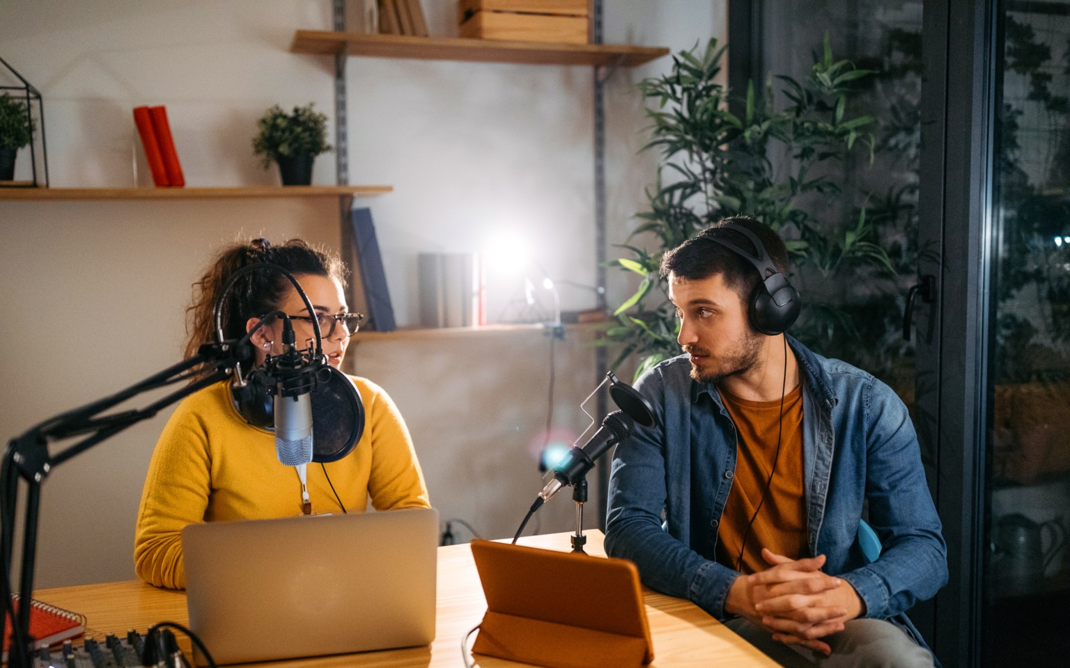 Photo of two young people recording a podcast in a studio