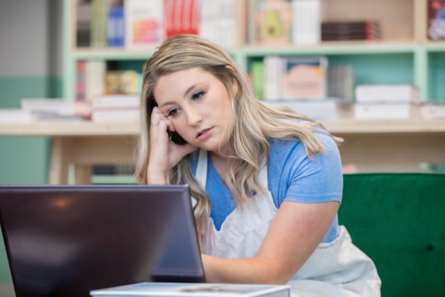 Frustrated small business owner looking frustrated while working on laptop in shop contacting customer service