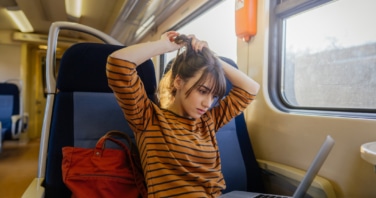 photo of woman working on a train with her laptop on her lap