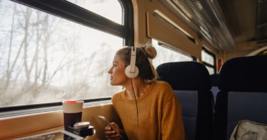 woman riding a train looking out of the window wearing headphones