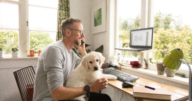 Man working from home with cute puppy on his knee-709