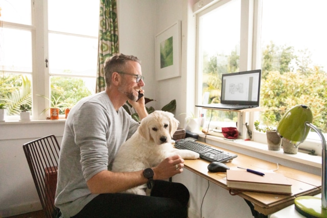 Man working from home with cute puppy on his knee-709