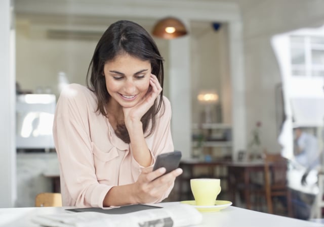 Smiling businesswoman looking down at cell phone in cafe window-488