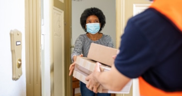 female customer wearing a mask receiving a delivery in the doorway