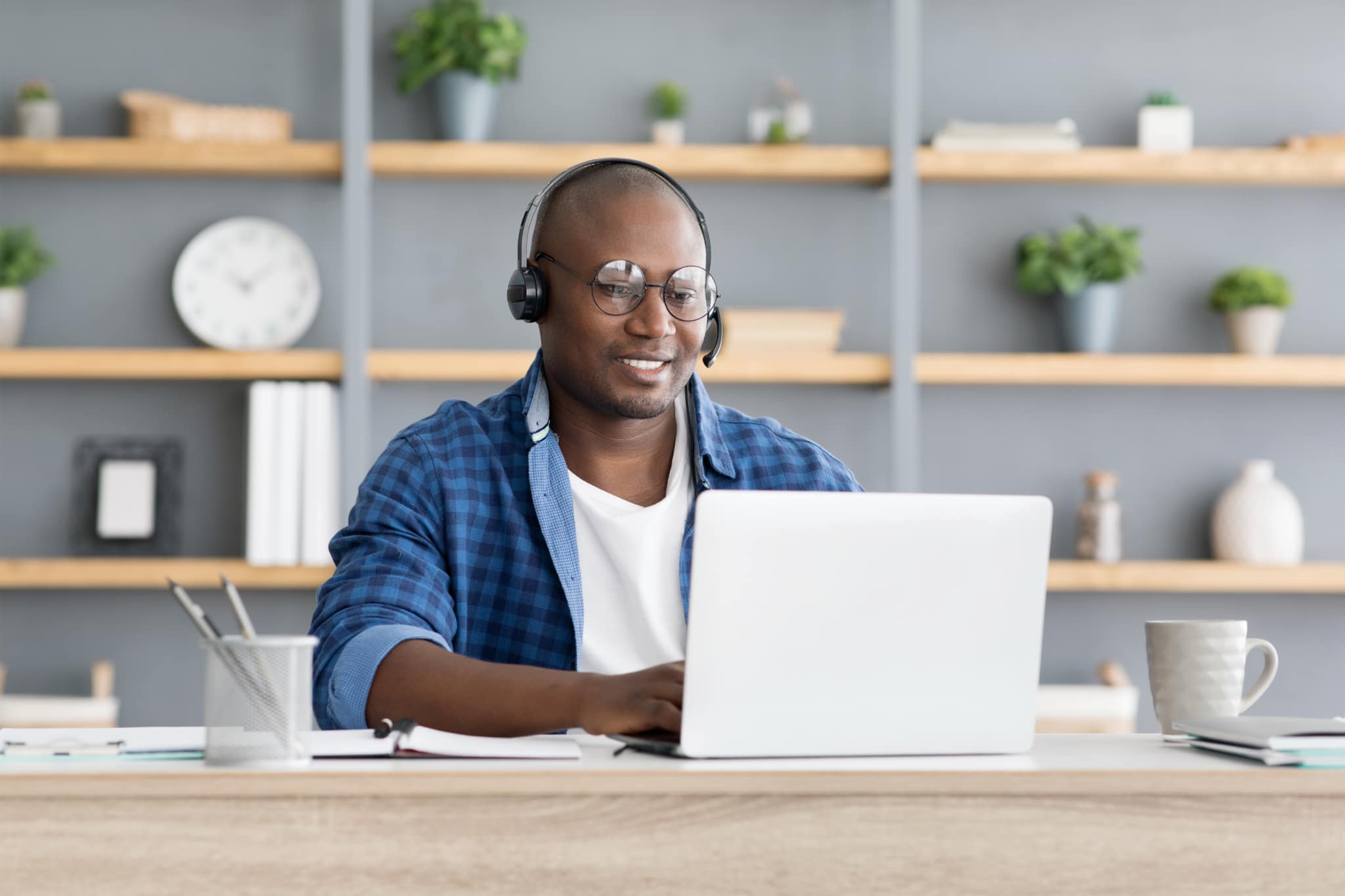 Hotline support service. African american male call center operator in headset working with laptop computer at home