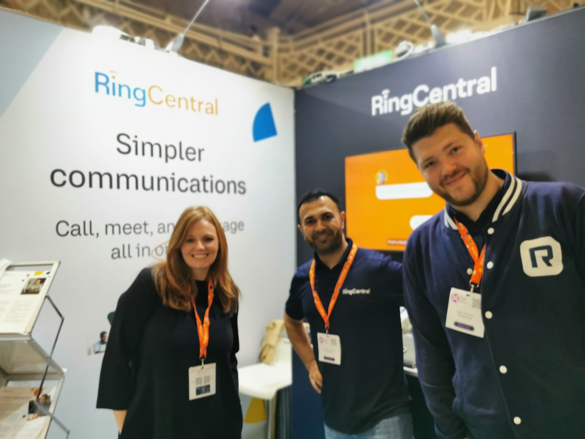 Three people smiling for the camera in front of the RingCentral stand