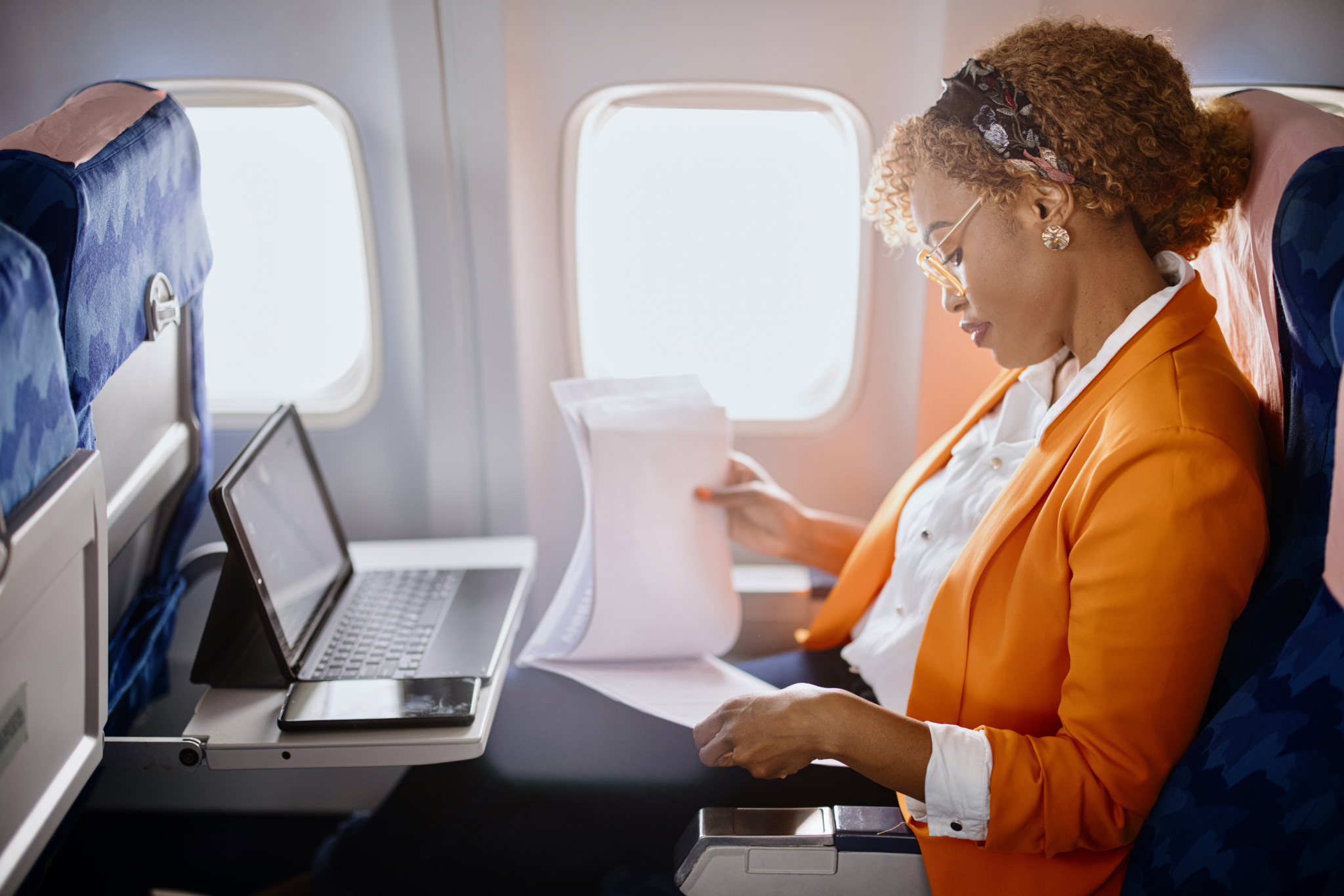  A woman working while traveling on a plane.