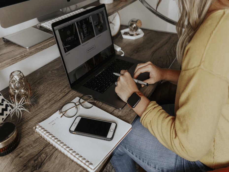 Woman in denim jeans and sweatshirt working from home on a laptop