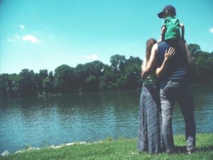 young family standing in front of lake