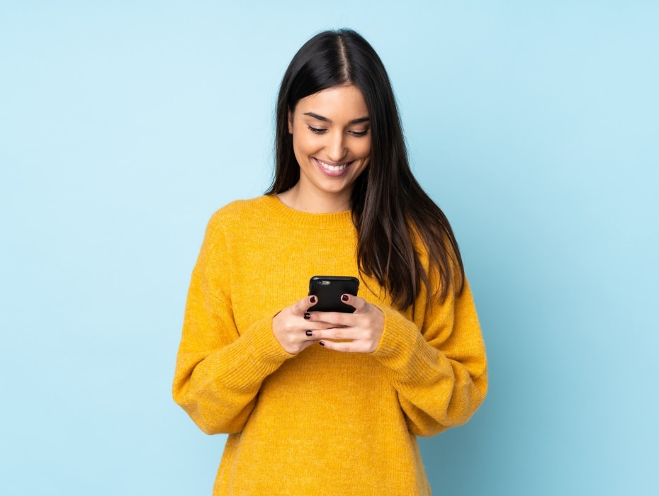 Young caucasian woman isolated on blue background sending a message with the mobile