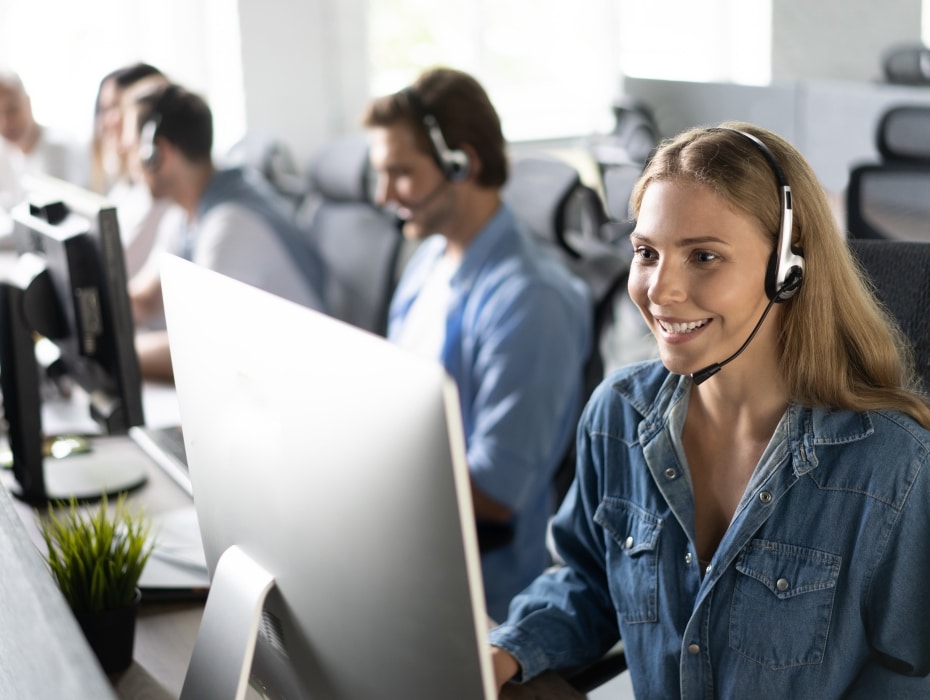 How can I help you? Beautiful call center workers in headphones are working at modern office