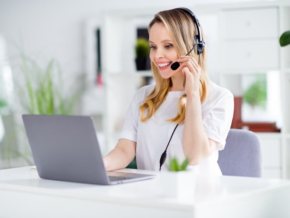 Portrait of attractive cheerful focused girl using laptop consulting clients answering calls at light white home house indoors