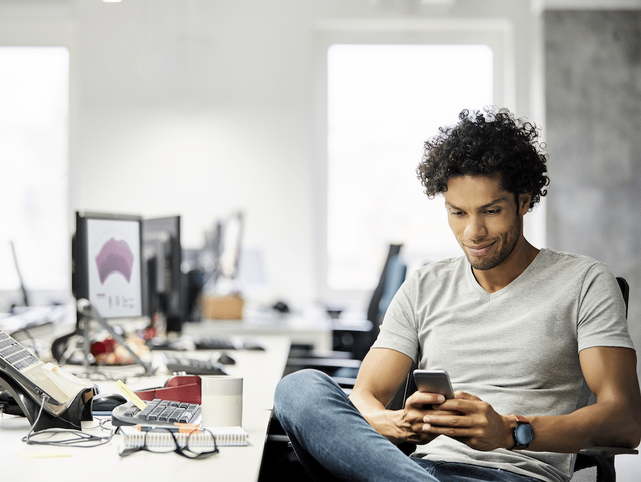 Male entrepreneur SMS messaging while sitting at desk