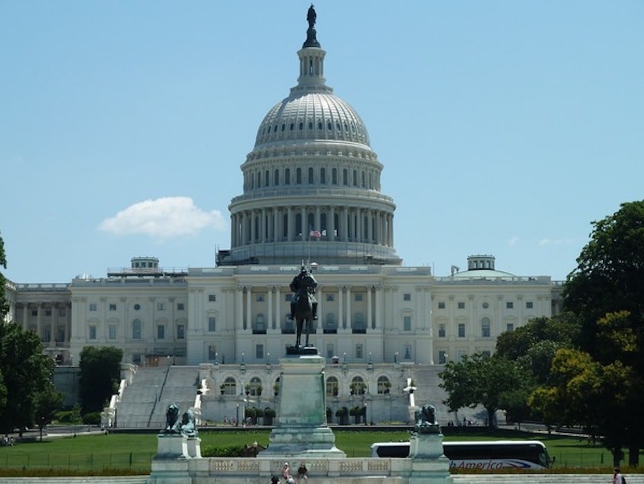 Picture of the US Capitol Building on a sunny day with blue skies and a fountain in front