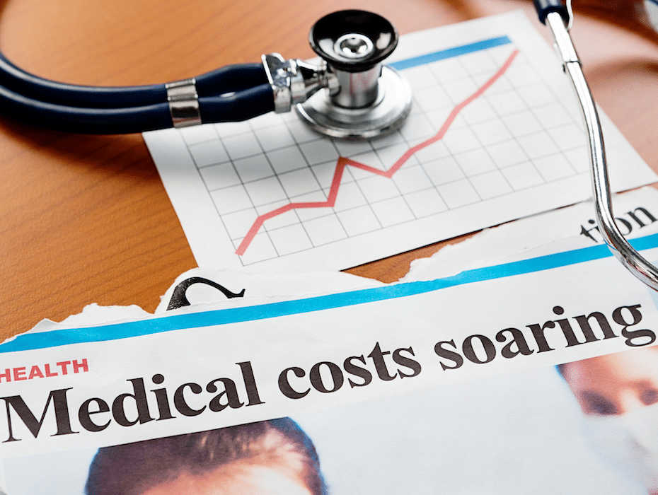 An image with a stethoscope on a desk above a newspaper with the headline "Medical costs soaring"