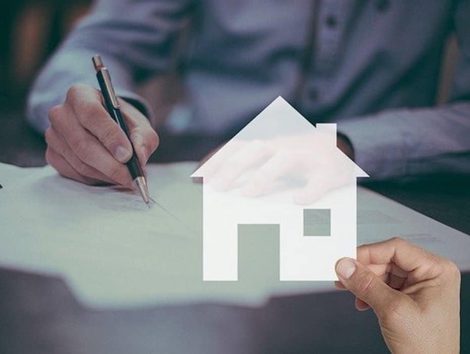 Insurance customer signing paperwork with an image of a house laid over the picture to symbolize the life event of buying a new house