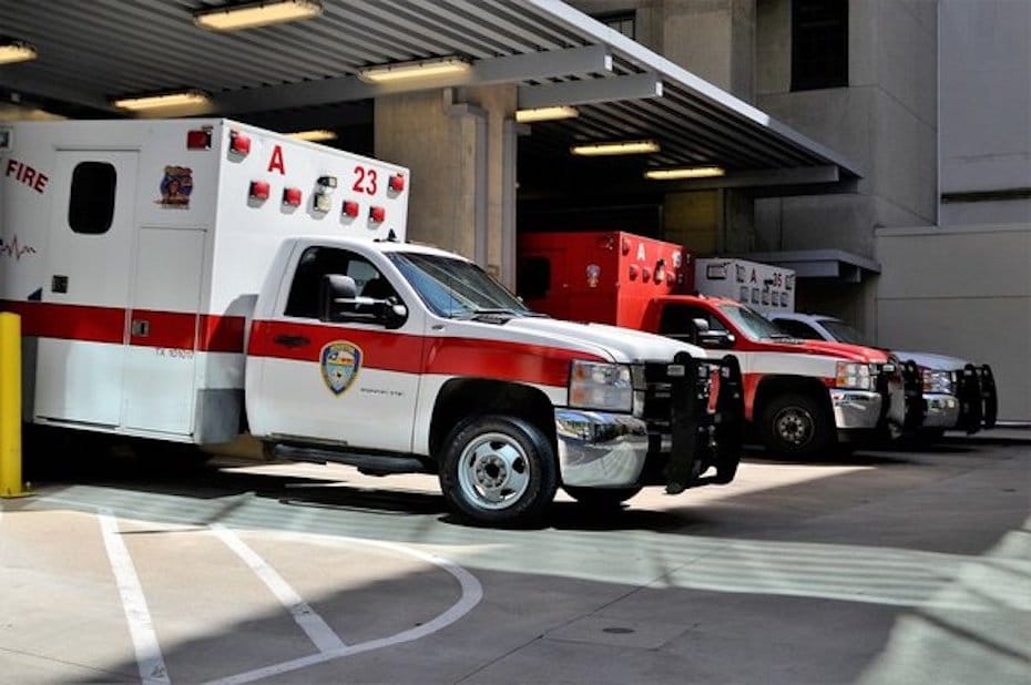 Side view of an ambulance and other emergency vehicles parked in a large garage
