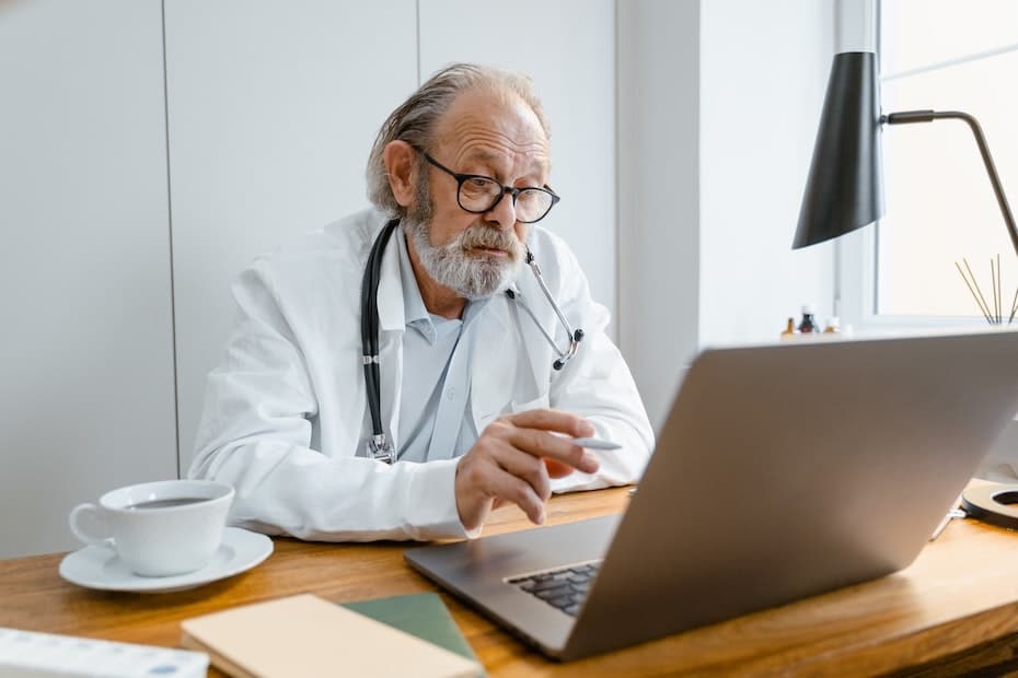 Healthcare providers uses a laptop at his desk leveraging cloud-based communications to ensure continuity of care.