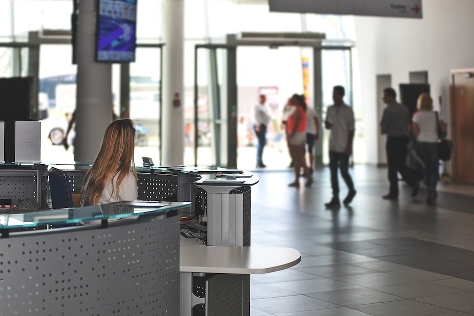 A government employee sits at a central greeting station in the lobby of a building