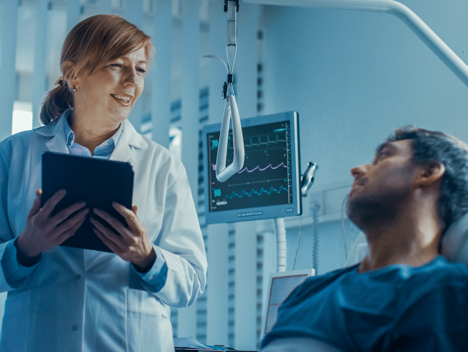 Physician works into the late-night hours by attending to a patient lying in a hospital bed