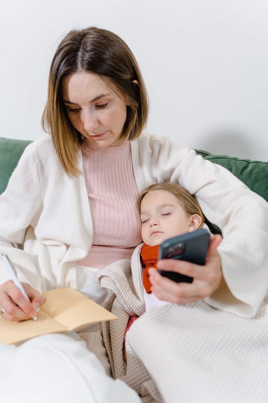 A mother at home with her sick sleeping child, using her mobile for a telehealth session
