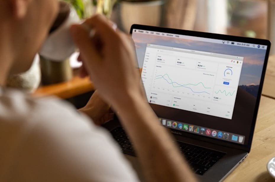 Financial services employee drinking coffee and working on their laptop while working from anywhere.