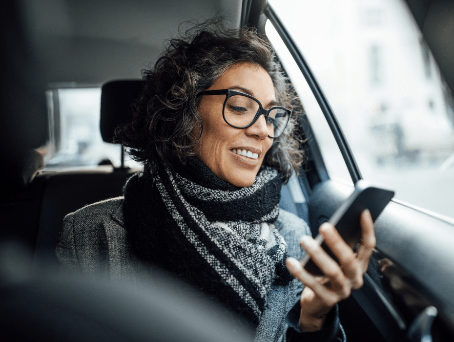Woman in the backseat of a car talking on a smartphone
