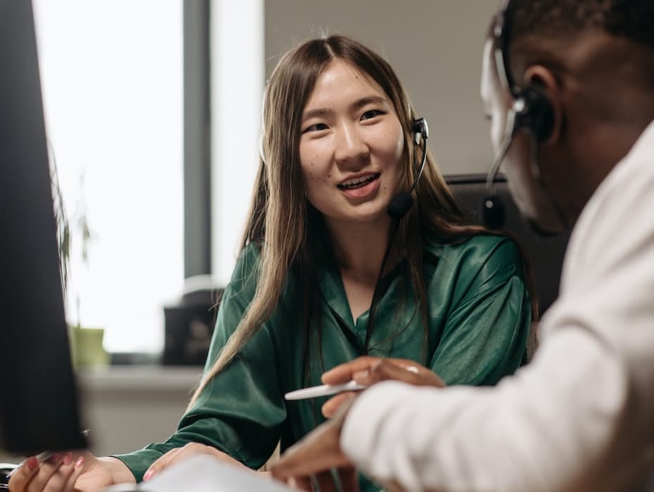 Two financial services contact center agents having a discussion in front of a computer