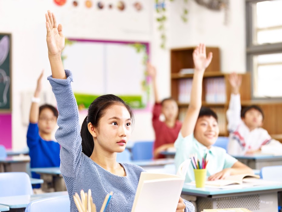 A student raises her hand within a classroom setting