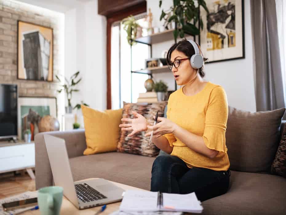 Woman working from home is on her computer, wearing headphones.