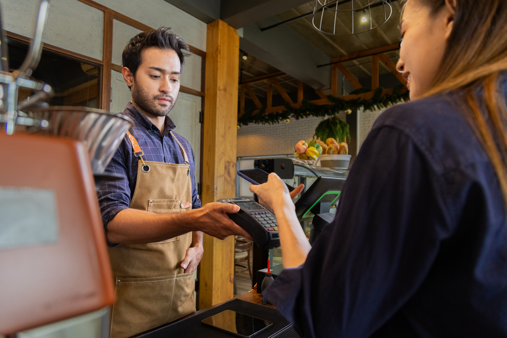Customer tapping her phone for contactless payment in-store