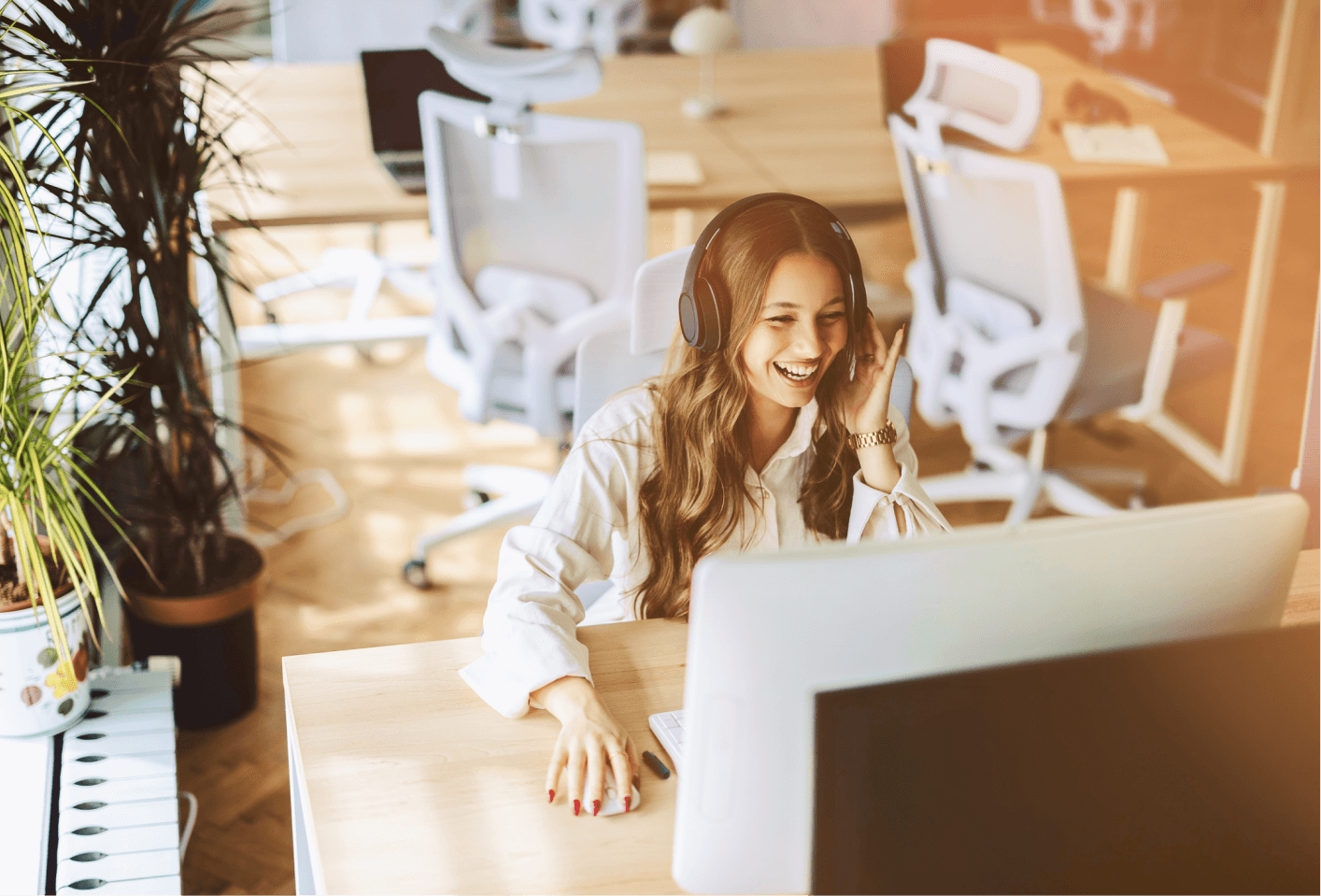 A woman sits at a desk, focused on her computer screen, with a notepad and pen beside her.