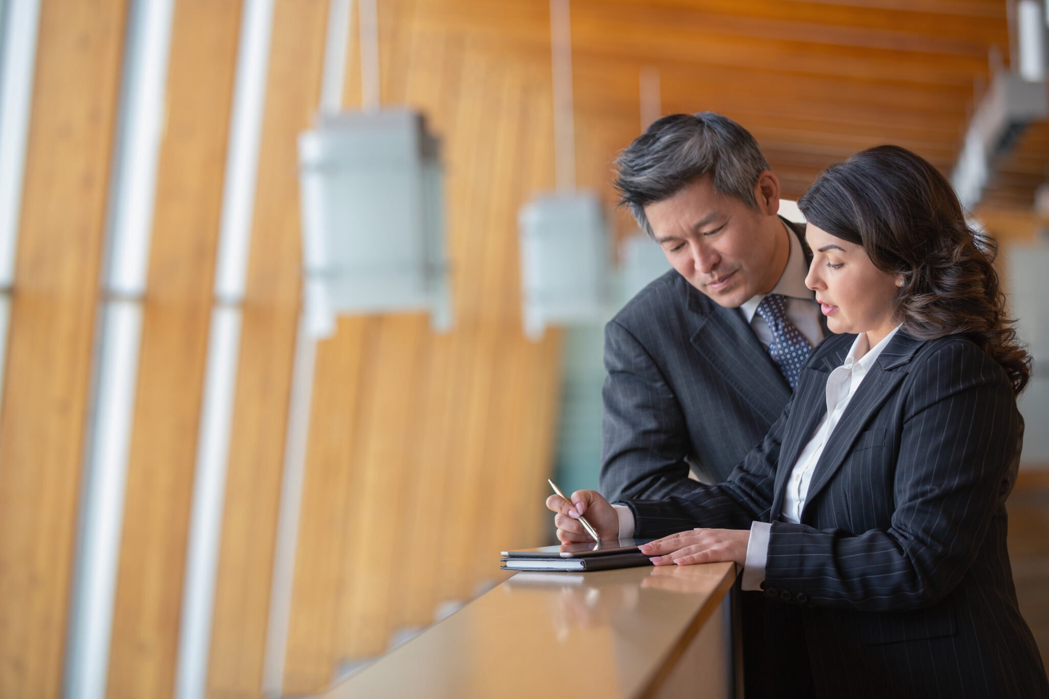 Two bank executives in a discussion while looking at a tablet on a desk