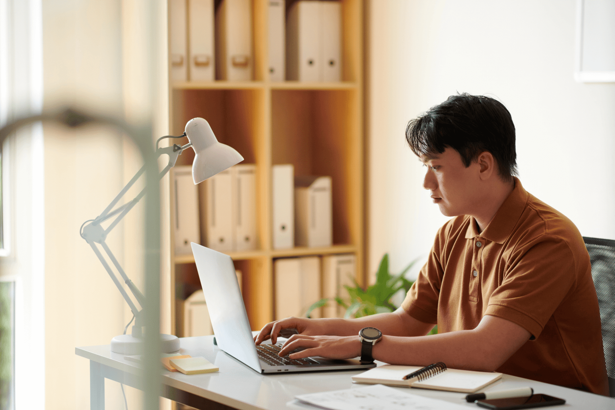 A contact center manager checks the RingCX workforce management interface on his laptop in his office